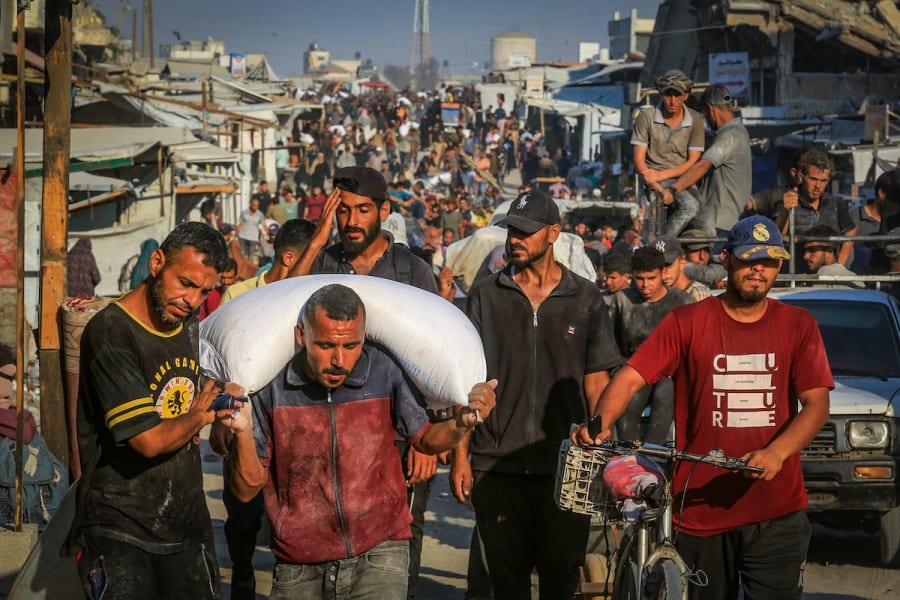 Illustrative - Palestinians walk through the streets with bags of flour after humanitarian aid trucks arrived via the Israeli-controlled Kerem Shalom crossing into southern Gaza, in Khan Younis, July 24, 2025.( Photo: Abed Rahim Khatib/Flash90)