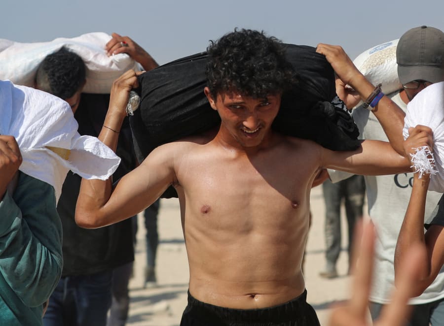 Palestinians carry aid supplies that entered Gaza through Israel, in Beit Lahia, northern Gaza Strip, August 2, 2025. (Photo: REUTERS/Mahmoud Issa)
