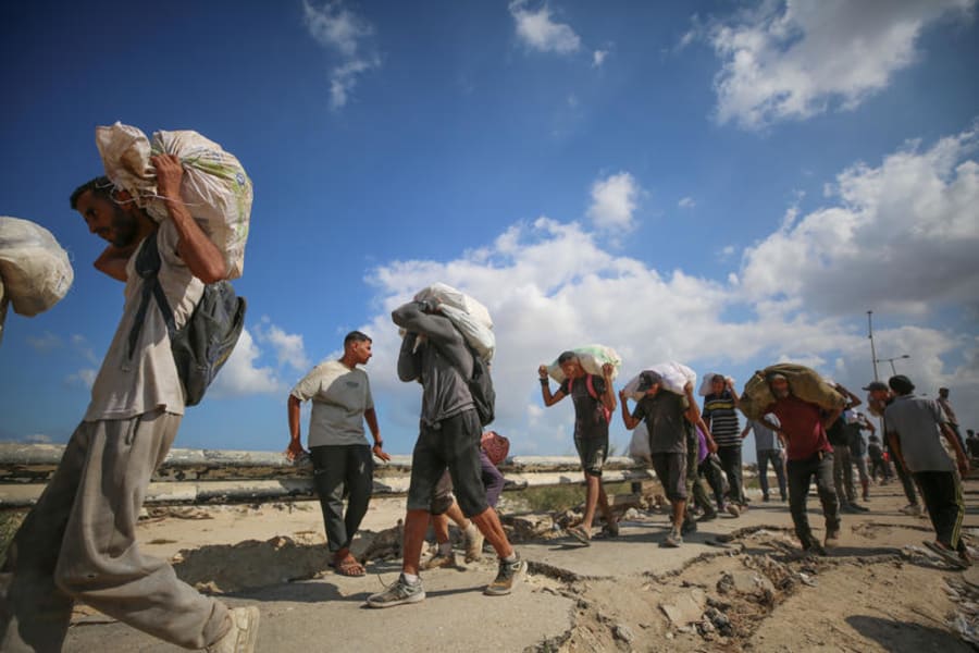 Des Palestiniens déplacés transportent des colis alimentaires et des fournitures depuis un point de distribution d'aide du GHF dans le "couloir de Netzarim" au centre de Gaza, le 5 août 2025. (Photo : Ali Hassan/Flash90)