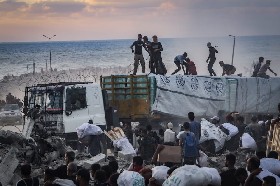 Armed Palestinians sit on trucks carrying humanitarian aid near the Zikim border crossing between Israel and Beit Lahia in the northern Gaza Strip, August 18, 2025. (Photo: Khalil Kahlout/ Flash90)