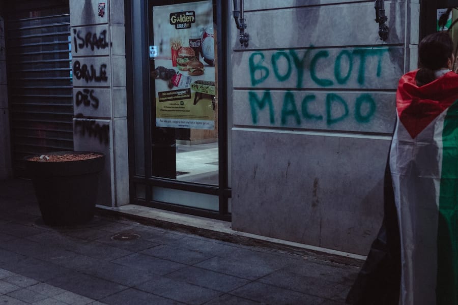 A protester with a Palestinian flag stands in front of a Macdonald's restaurant that is spray painted BOYCOTT MACDO during a pro-Palestinian demonstration in Lyon, France, October 14, 2024. (Photo: Elsa Biyick / Hans Lucas via Reuters)