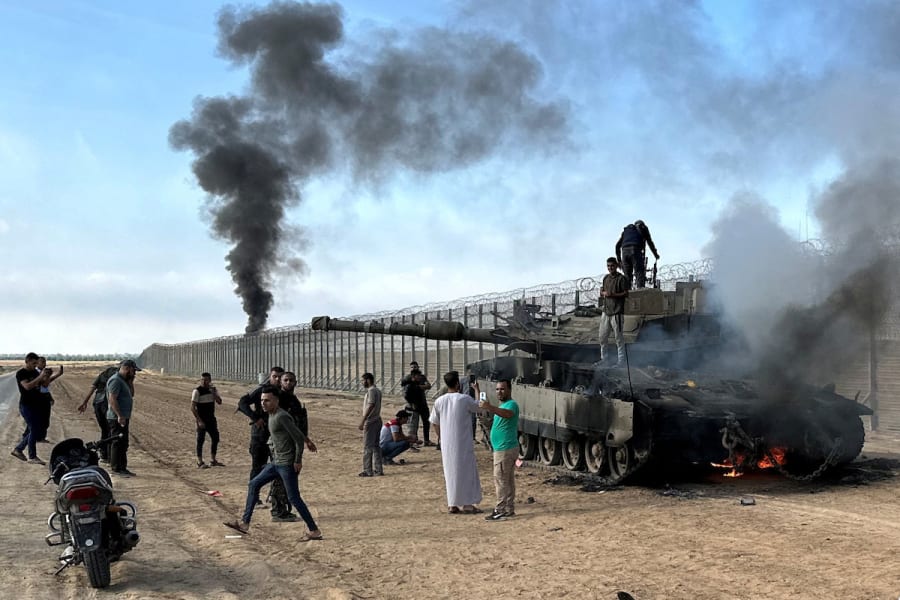 Palestinians react as an Israeli tank burns after it was hit by Hamas terrorists who infiltrated areas of southern Israel, Oct. 7, 2023. (Photo: REUTERS/Mohammed Fayq Abu Mostafa)