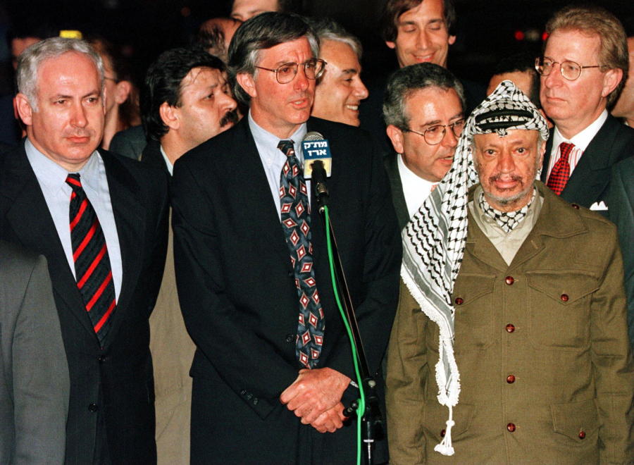 File Photo: Palestinian President Yasser Arafat (R) and Israeli Prime Minister Benjamin Netanyahu (L) listen as United States special envoy Dennis Ross speaks on the border of the Gaza Strip about an agreement the Clinton administration had brokered between the two leaders. (photo credit: Reuters)
