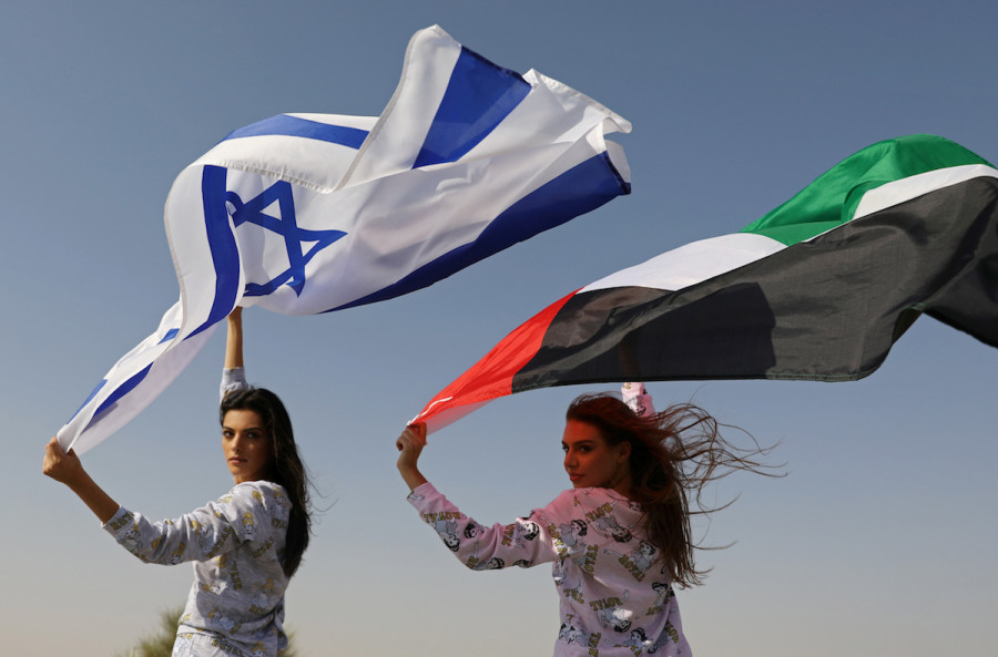 Israeli model May Tager, holding an Israeli flag, poses with Dubai-resident model Anastasia, holding an Emirati flag, during a photoshoot for Israeli brand FIX in Dubai. (Photo credit: REUTERS/Christopher Pike)