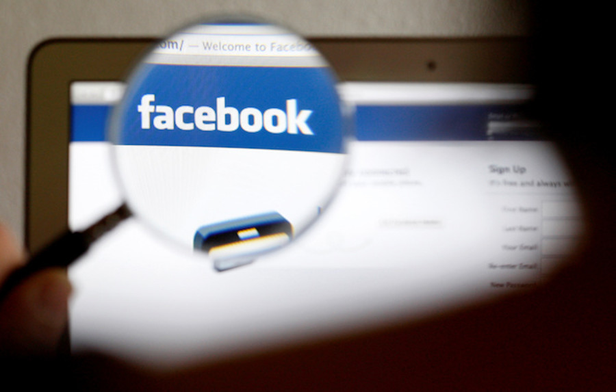 In this photo illustration, a Facebook logo on a computer screen is seen through a magnifying glass held by a woman in Bern May 19, 2012. REUTERS/Thomas Hodel