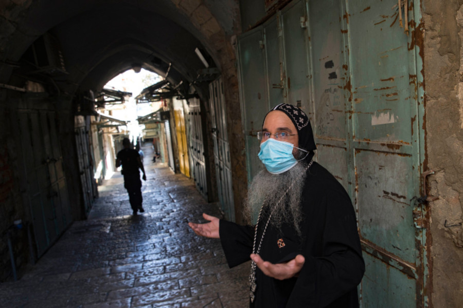 A priest walking next to closed shops in Jerusalem's Old City during a nationwide lockdown. (Photo: Nati Shohat/Flash90)