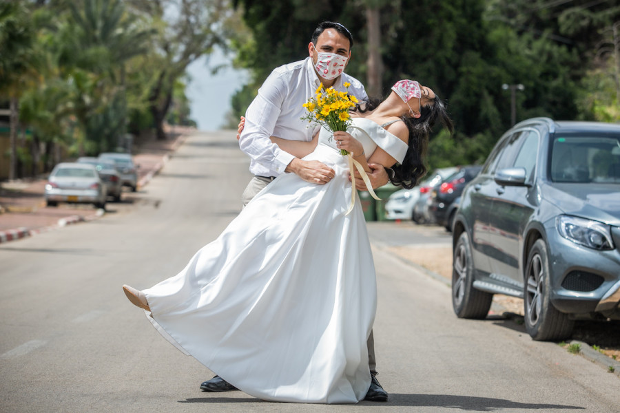 Gal Sade Knigsfild and Nofar Almakias pose for a picture with face mask before their wedding on April 6, 2020, after their wedding was cancelled due to new regulations following the spread of the coronavirus. (Photo: Yossi Aloni/Flash90)
