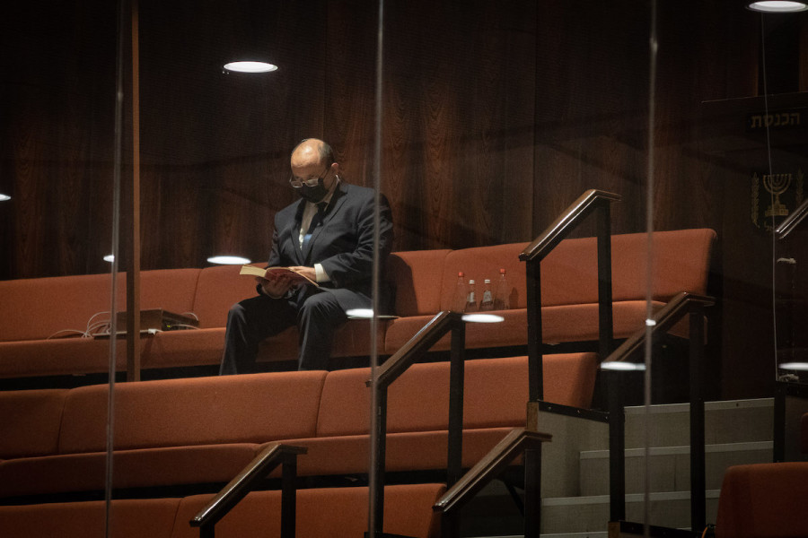 Israeli Prime Minister Naftali Bennett in the quarantine chamber during a plenum session in the Knesset assembly hall, Dec. 27, 2021. (Photo: Noam Revkin Fenton/Flash90)