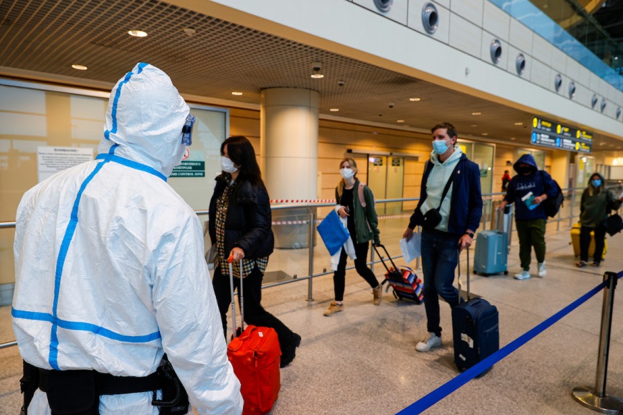 An airport employee in a protective suit and Russian tourists arriving from South Africa at Moscow's Domodedovo International Airport, Dec. 4, 2021 (Photo: Mikhail Japaridze/TASS)