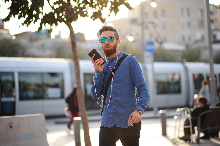 Illustrative - Israeli on his phone walking in the street in Jerusalem (Photo: Mendy Hechtman/Flash90)
