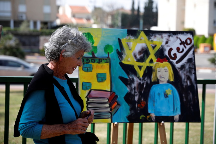 Rama Reiss Kremnicer, a Holocaust survivor, stands next to a painting that is part of an initiative in which students created paintings inspired by Holocaust survivors' stories, as Israel marks its annual Holocaust Remembrance Day, in Ashkelon, April 8, 2021. (Photo: REUTERS/Amir Cohen)