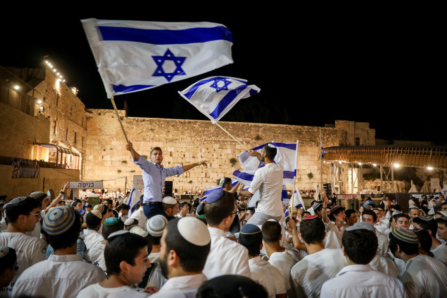 Jewish young men dance with Israeli flags at the Western Wall in Jerusalem's Old City on the eve of Jerusalem Day, May 28, 2022. (Photo: Noam Revkin Fenton/Flash90)