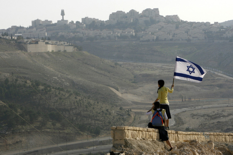 An Israeli holds a national flag on a hilltop near Ma'ale Adumim December 9, 2007. (Photo: REUTERS/Gil Cohen Magen)