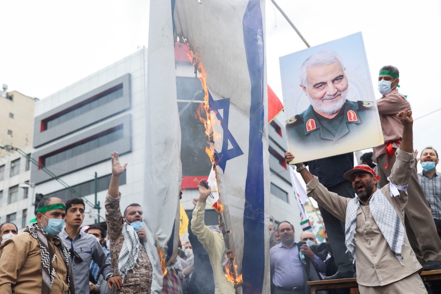 A man holds up a poster of the late Iranian Major-General Qassem Soleimani next to a burning Israeli flag as Iranians attend a rally marking the annual Quds Day, or Jerusalem Day, on the last Friday of the holy month of Ramadan in Tehran, Iran, April 29, 2022. (Photo: Majid Asgaripour/WANA via REUTERS)