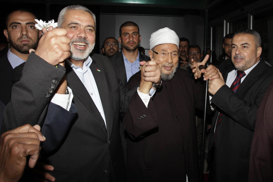 Hamas Prime Minister Ismail Haniyeh (L) holds the hand of Egyptian Cleric and chairman of the International Union of Muslim Scholars Sheikh Yusuf al-Qaradawi (C) upon al-Qaradawi's arrival at Rafah Crossing in the southern Gaza Strip, May 8, 2013. (Photo: REUTERS/Ibraheem Abu Mustafa