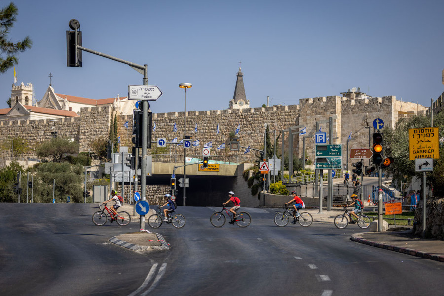 People ride their bicycles and walk along the empty road near the Old City walls in Jerusalem, on Yom Kippur, Oct. 4, 2022. (Photo: Yonatan Sindel/Flash90)