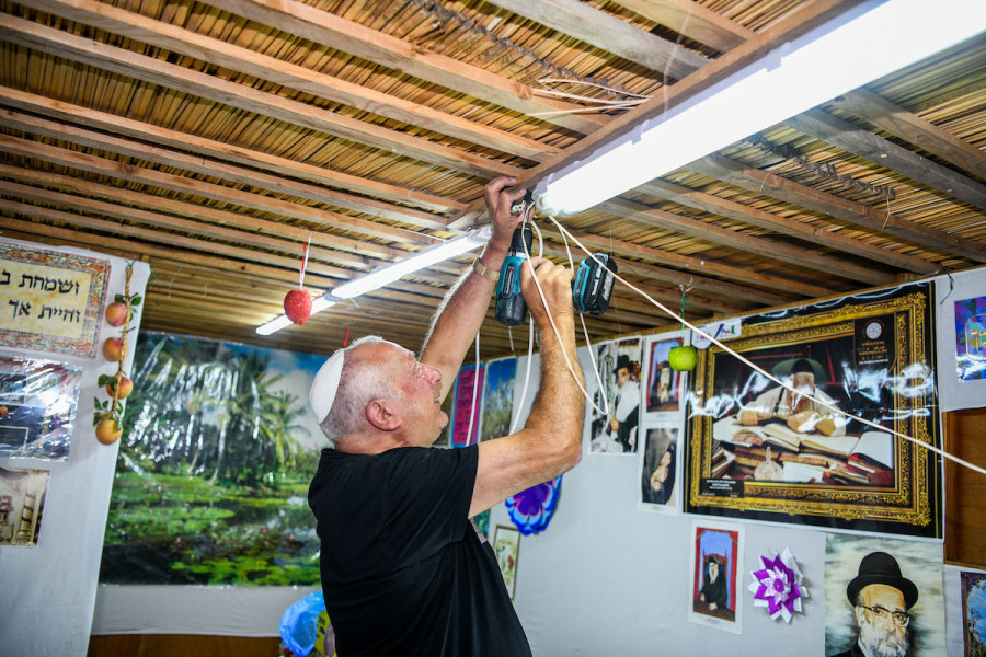 An Israeli builds and decorates a sukkah at the end of Yom Kippur for the upcoming holiday of Sukkot, in Jerusalem, Oct. 5, 2022. (Photo: Arie Leib Abrams/Flash90)