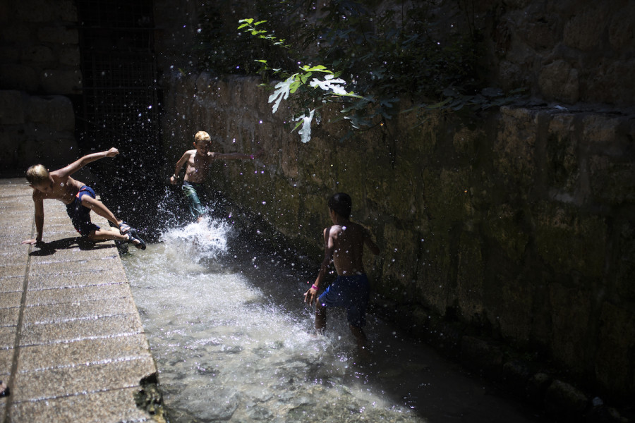 Young Israeli boys on their summer vacation play in the water of the Siloam Pool after walking through Hezekiah's Tunnel during their visit to the City of David National Park, July 21, 2019. (Photo: Hadas Parush/Flash90