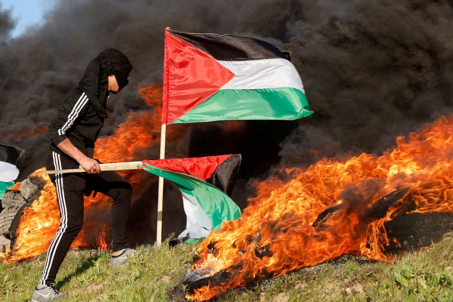 A man holds a flag as Palestinians clash with Israeli forces near the Israel-Gaza border, east of Gaza City, February 22, 2023. REUTERS/Mohammed Salem