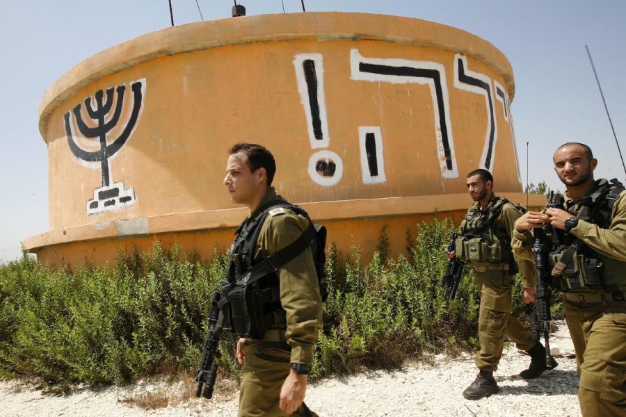 Israeli soldiers walk by the water tower on the ruins of the evacuated settlement of Homesh, Aug. 17, 2009. Homesh was one of four West Bank settlements that Israel evacuated during the disengagement. (Photo: Miriam Alster/Flash90)