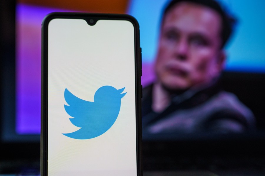 Twitter logo on a smartphone with Elon Musk in the background (Photo: Shutterstock)