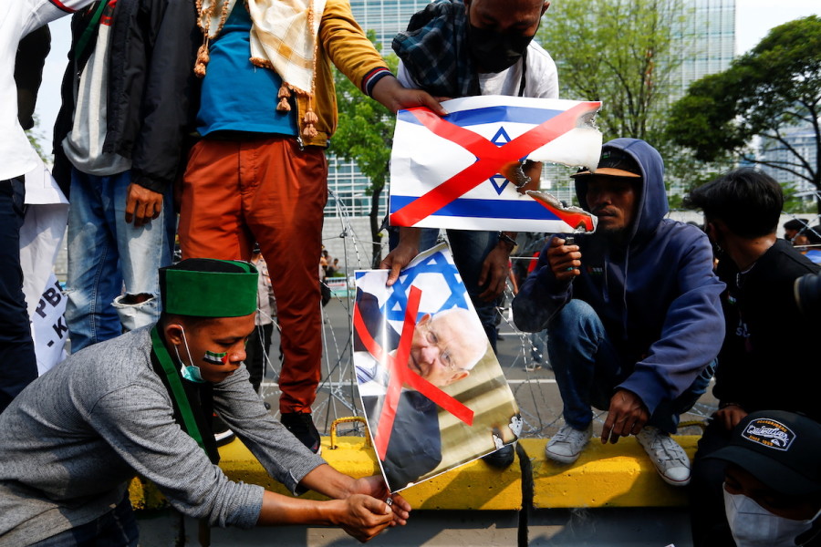 Protesters burn an Israeli flag and a picture of then-Israeli President Reuven Rivlin during a protest against Israel outside the U.S. embassy in Jakarta, Indonesia, May 21, 2021. (Photo: REUTERS/Ajeng Dinar Ulfiana)