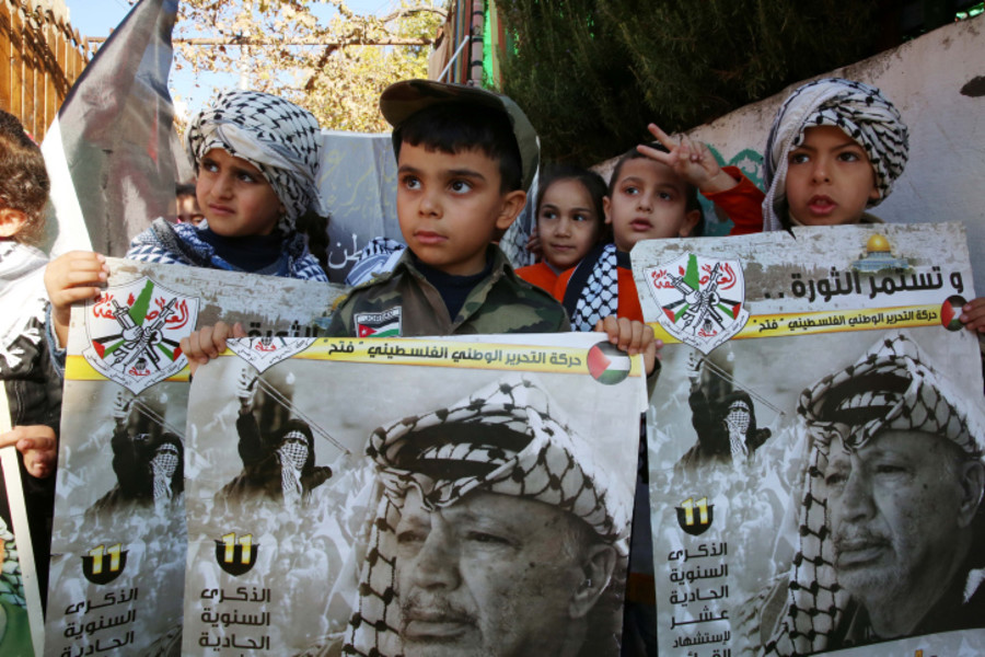 Palestinian children hold posters of the late Palestinian leader Yasser Arafat as they mark the 18th anniversary of his death, in the West Bank city of Hebron on November 10, 2022. Photo by Wisam Hashlamoun/Flash90