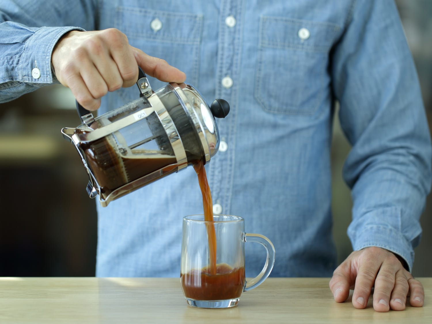 French press of coffee being poured into a glass mug