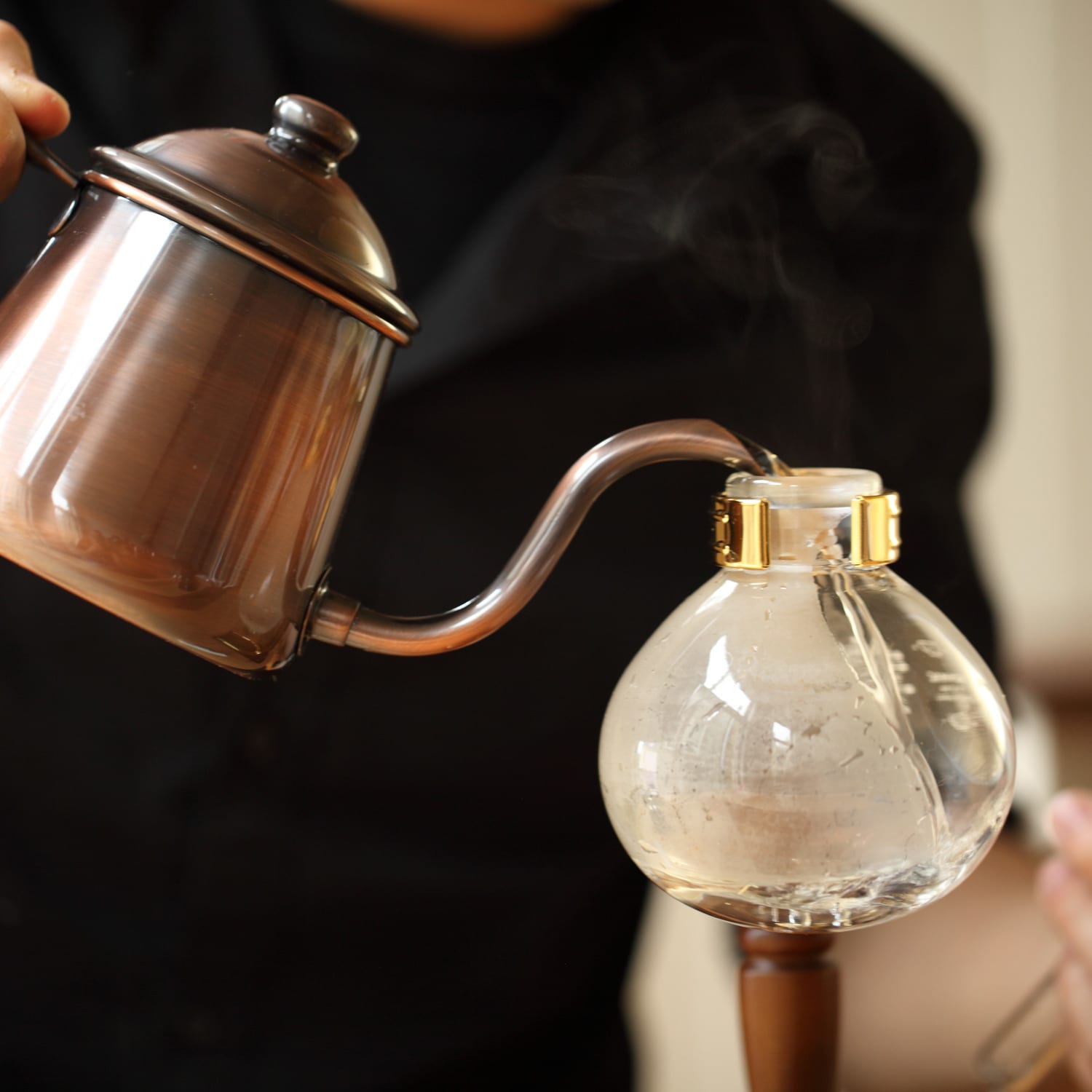 A kettle pouring water into a siphon