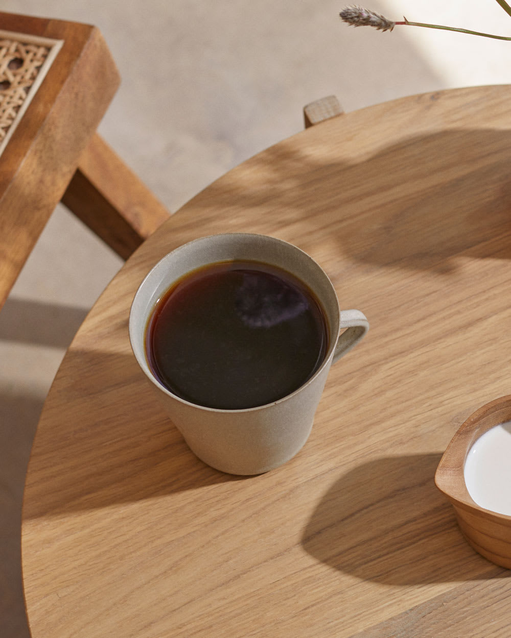 Cup of coffee with side on cream on a table.