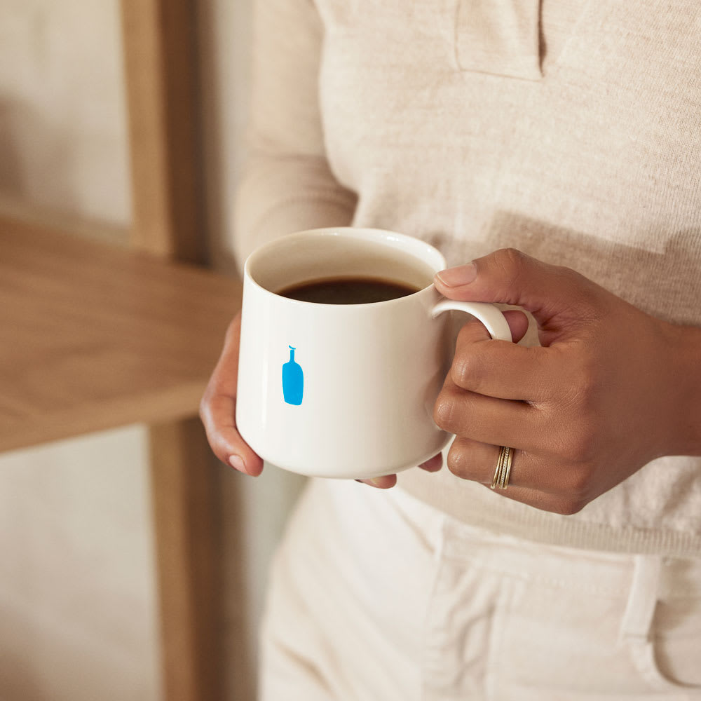Person holding a blue bottle mug full of coffee.