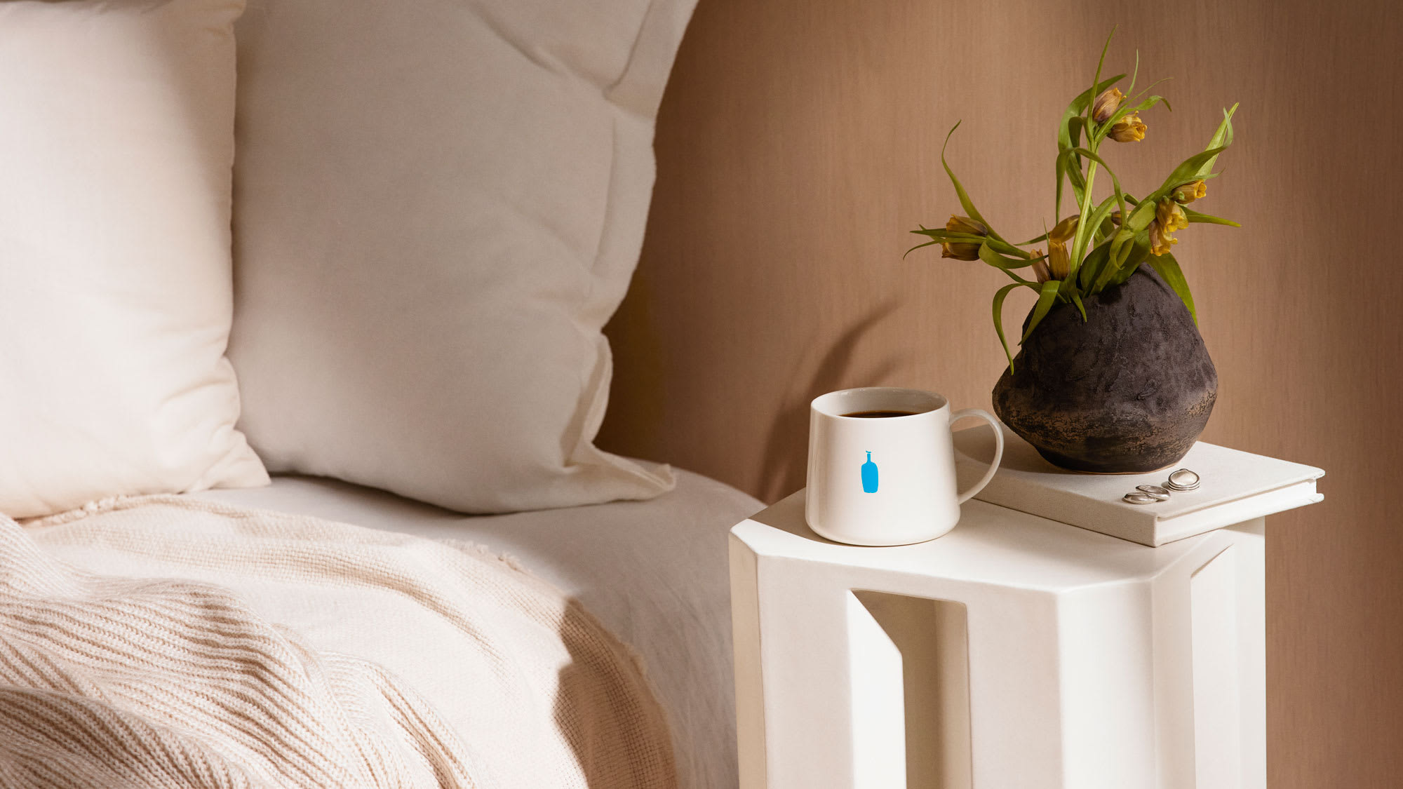 Blue bottle mug sitting on a bedside table.