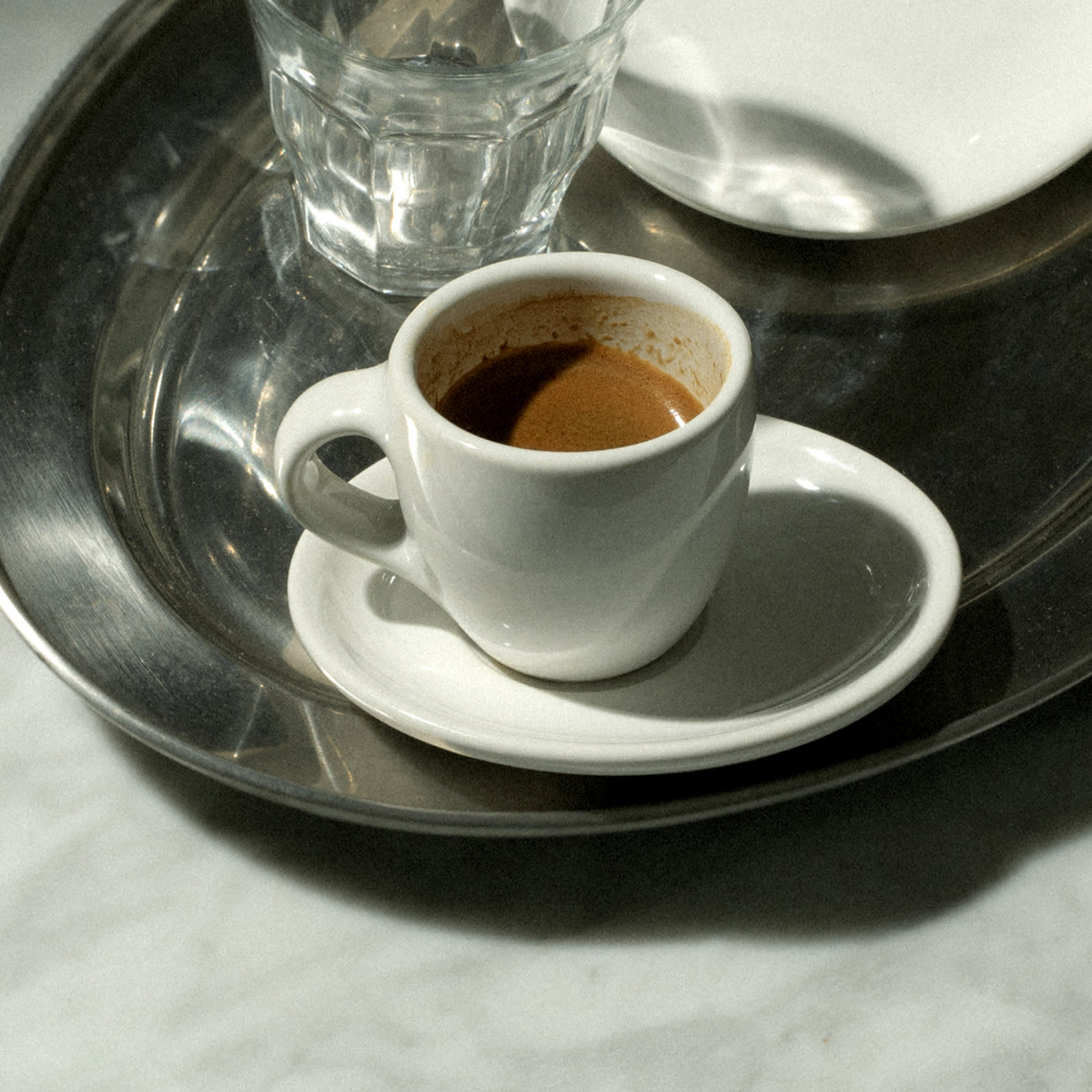 An espresso shot in a glass sitting on a table.