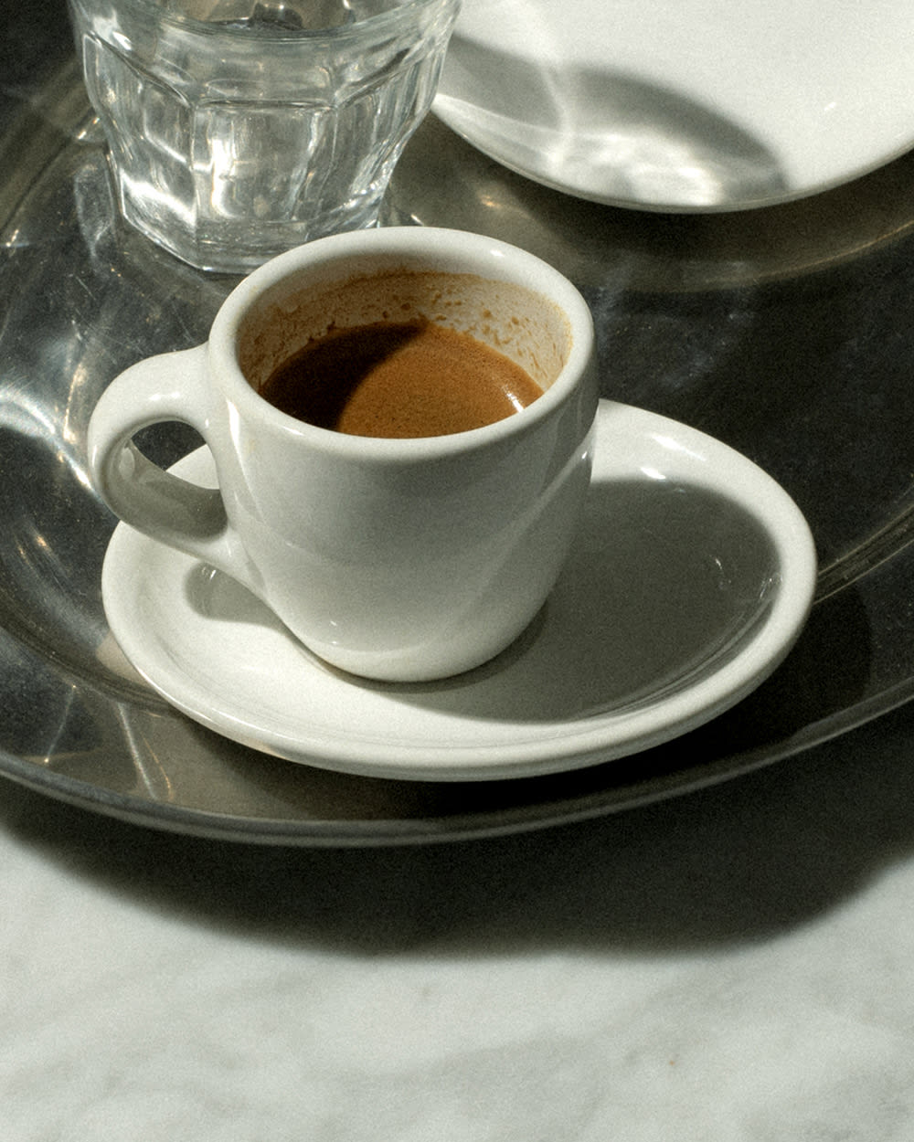 An espresso shot in a glass sitting on a table.