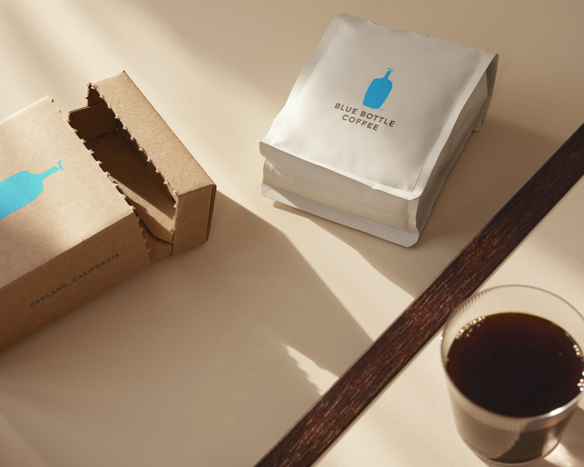 Blue Bottle Coffee Whole Bean Specialty Coffee Subscription Bag next to glass of coffee