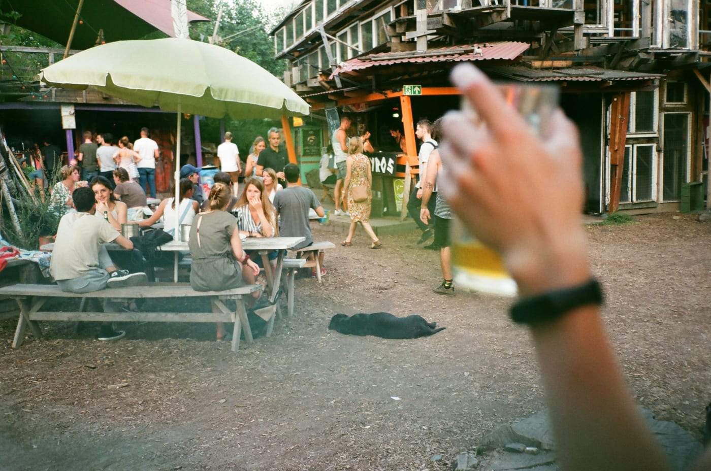 Lively scene from a street food festival with people enjoying themselves at tables under parasols in a relaxed atmosphere.