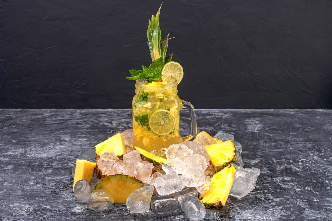 Refreshing Sparkling Pineapple Mojito with pineapple pieces, mint, and lime in a glass surrounded by ice cubes.