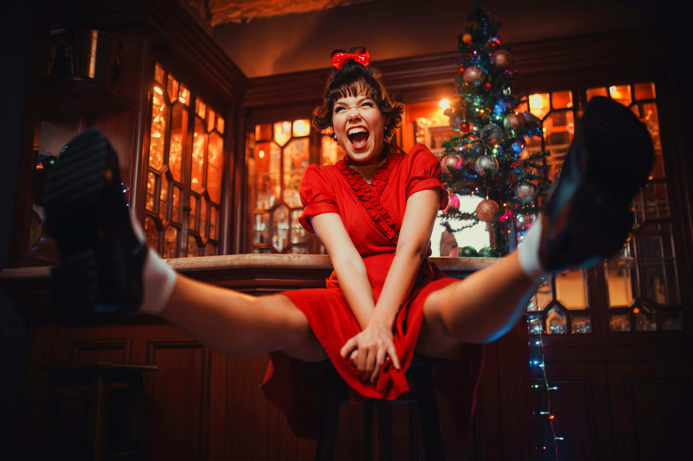 Festive Christmas setting with a woman in a red dress near a Christmas tree, symbolizing joy and festive atmosphere for a Christmas dinner.
