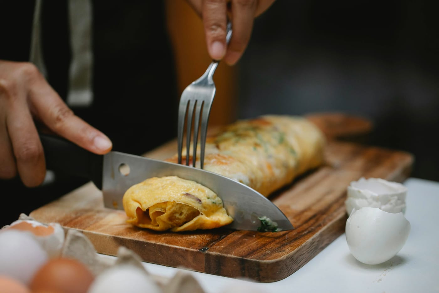 Professional chef preparing a gourmet dish by cutting an elegantly rolled omelet on a cutting board, highlighting customized menu planning and culinary flexibility.