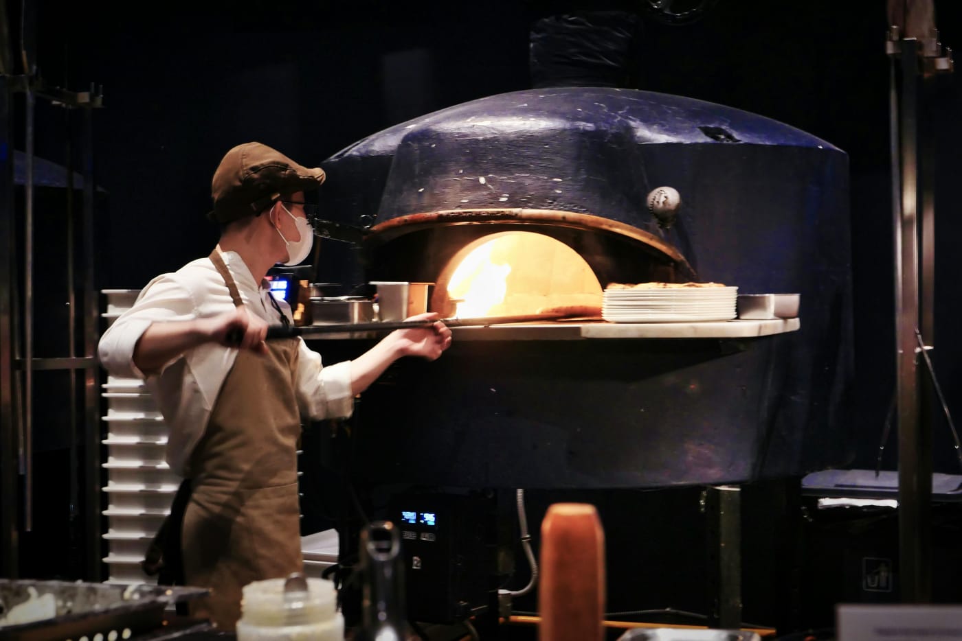 A chef stands in front of a large industrial oven, preparing food, supporting the articles focus on practical considerations of hiring a chef for weddings.
