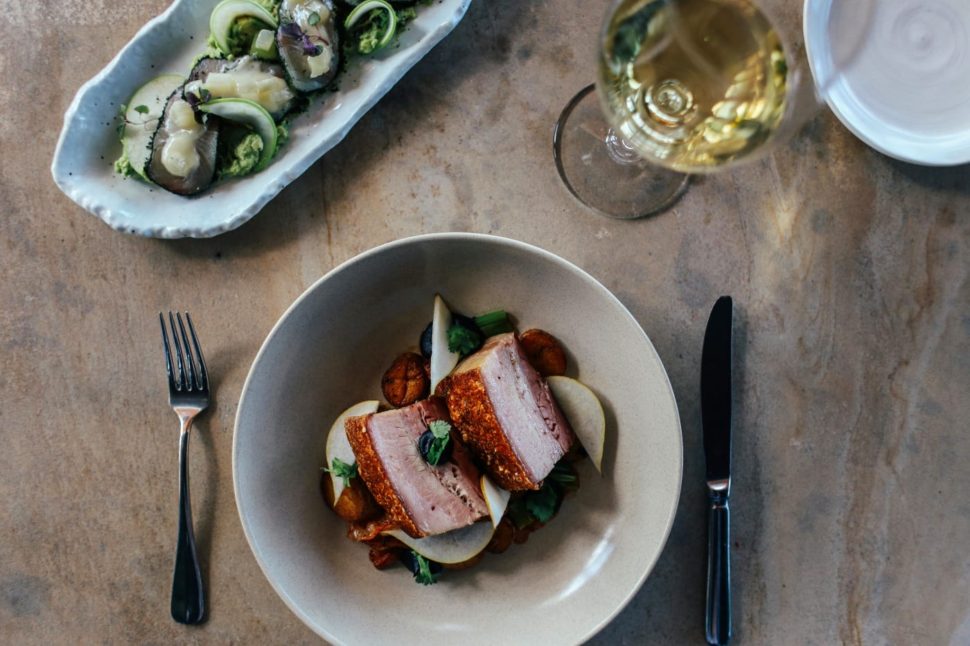 Elegant presentation of small dishes and a glass of wine, representing a modern tasting menu for weddings.