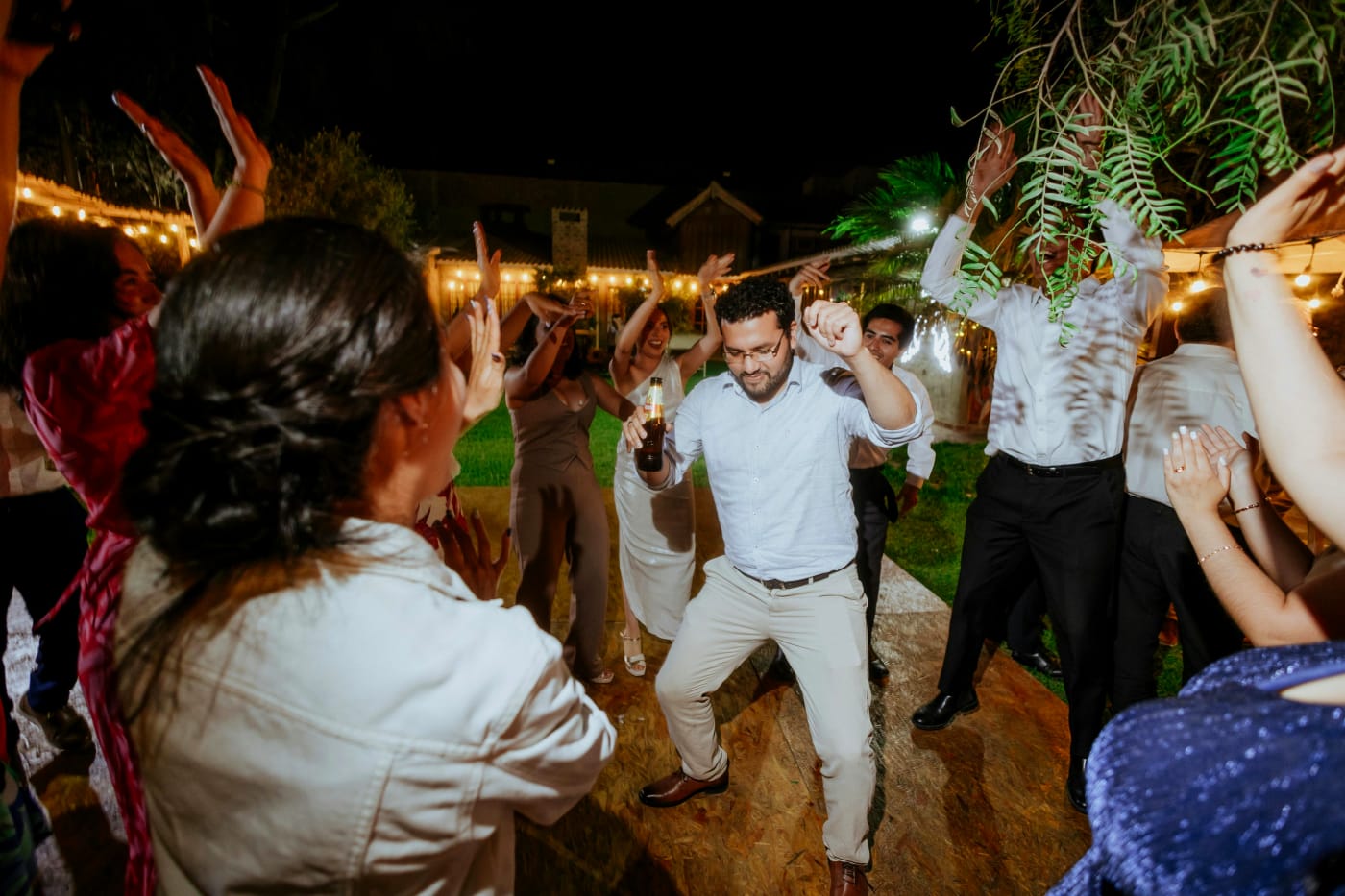 Party-loving guests dancing to energetic music under a night sky with string lights – perfect atmosphere for a birthday party.