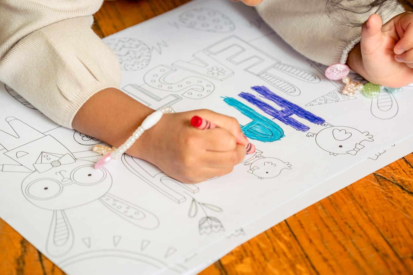 Child drawing creative motifs for birthday party, with colorful pencils and paper.