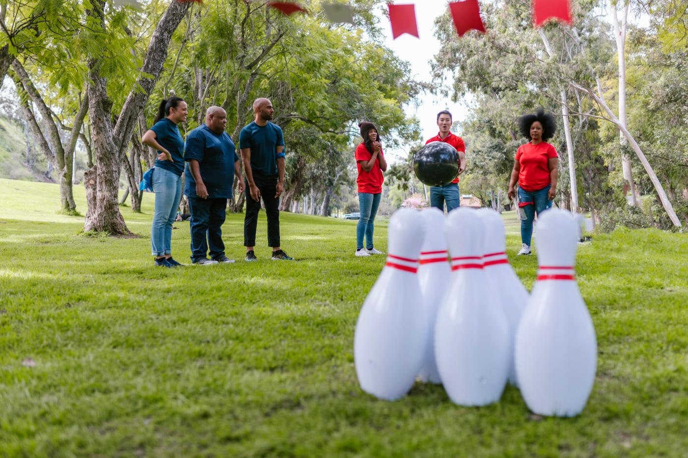 Group of people engaged in outdoor games with cones on a green lawn.