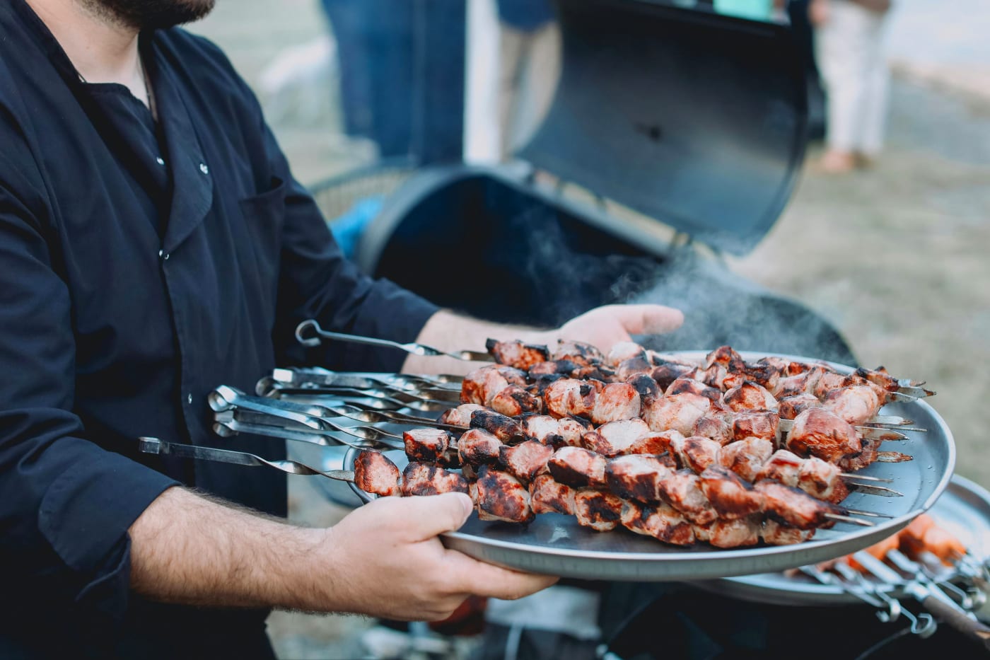A private chef serves grilled skewers at a party, illustrating ChefMes ability to offer tailored culinary experiences.