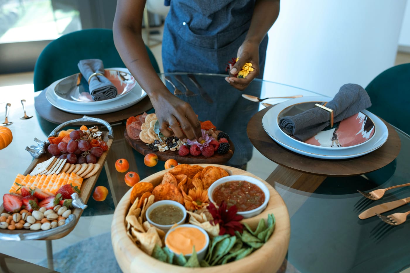 A chef decorates an elegant serving with snacks and dips on a beautifully set table, ideal for a 60th birthday.