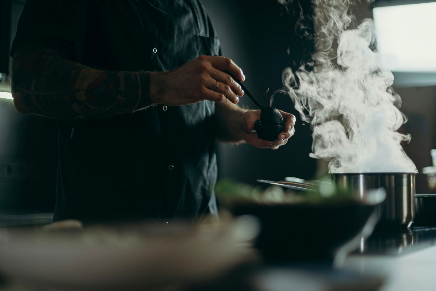 Hired chef preparing food in the kitchen with steaming pots, perfect for a 60th birthday party.