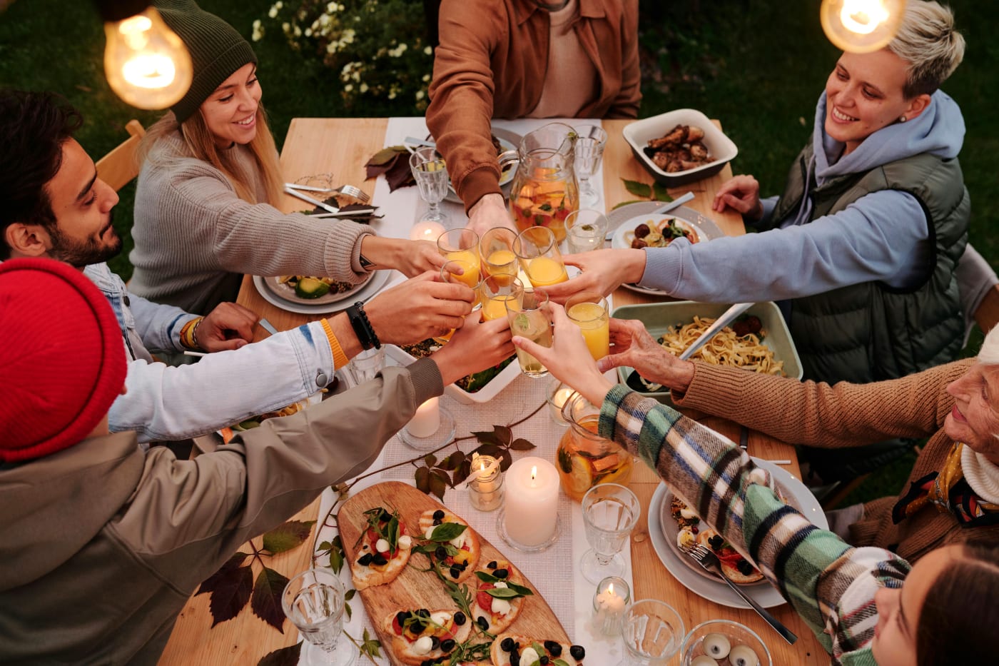 Group of people at a party enjoying dinner and toasting with various drinks, suitable for party planning and menu selection.