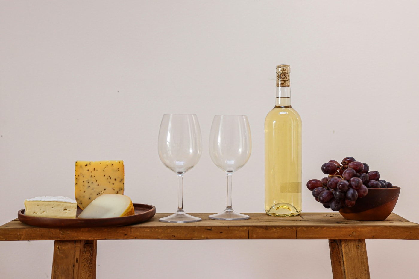 Elegant cheese platters with assorted cheeses, grapes, and white wine setup ready for festive appetizers.