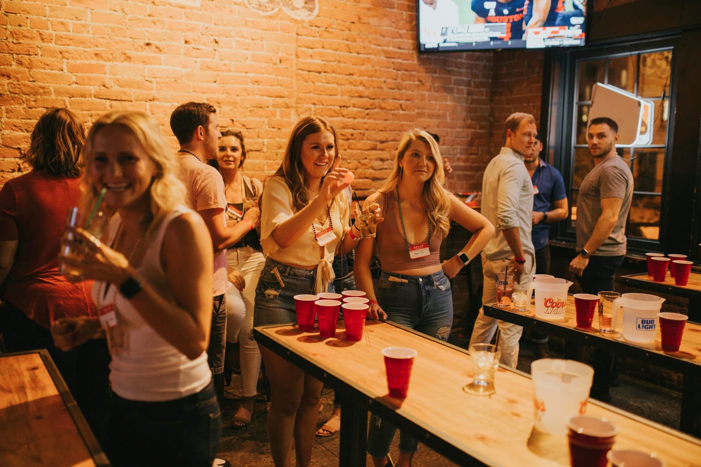 Young people playing beer pong at an American theme party, surrounded by a casual party atmosphere.